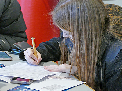 Studentin fllt ein Formular aus am Welcome Desk