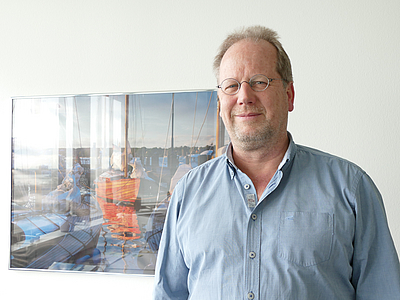 Portrait von Andree Hagedorn vor einem an der Wand h?ngenden Bild.