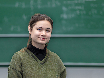 Adela Talipov, Frhstudentin an der Universit?t Bremen, steht vor einer Tafel in einem H?rsaal.
