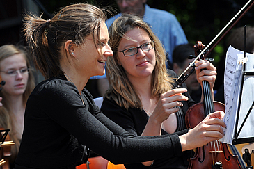 Zwei Frauen mit Geigen schauen auf ein Notenblatt